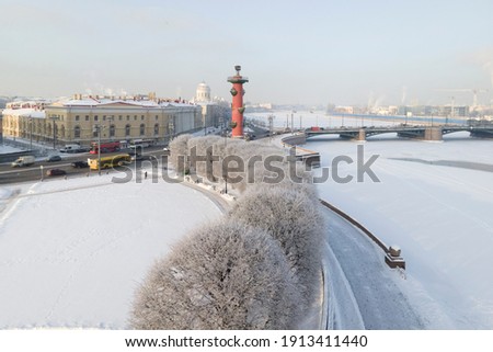 Aerial view of red rostral column on Vasilyevski spit in winter with frosty trees in the foreground