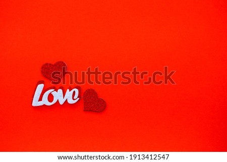 Valentine's day red background with wooden hearts and the word love. Place for inscriptions, advertising
