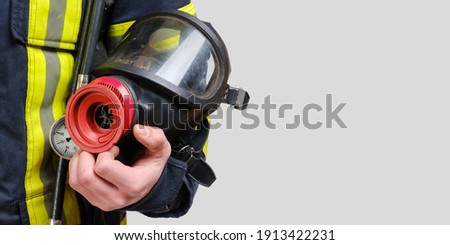 Full protective breathing mask in hand of unrecognized firefighter, rescue and fire fighter equipment isolated on gray background, copy space Royalty-Free Stock Photo #1913422231