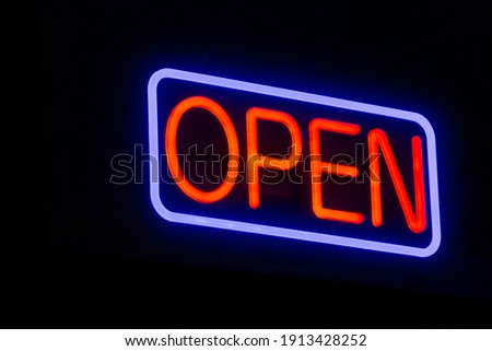Neon Light "Open" Sign hanging above building at night.