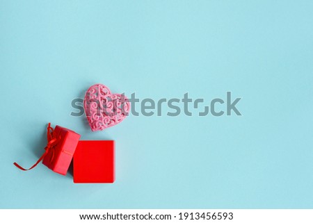 Valentine's Day background. A red gift box and a pink heart on a blue background. The concept of Valentine's Day. Flatlay, top view, copy space