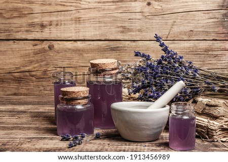 Dried lavender flowers in a in a mortar and pestle with bottle of essential lavender oil or infused water. Old books and lavender flowers bunch in the wooden background, place for text Royalty-Free Stock Photo #1913456989
