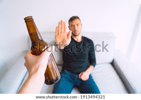 No alcohol. Young man refuses to drink beer, making stop gesture to bottle of beer