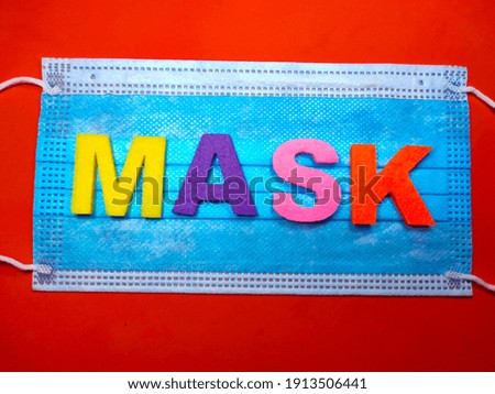 Selective focus.Word MASK on face mask with red background.