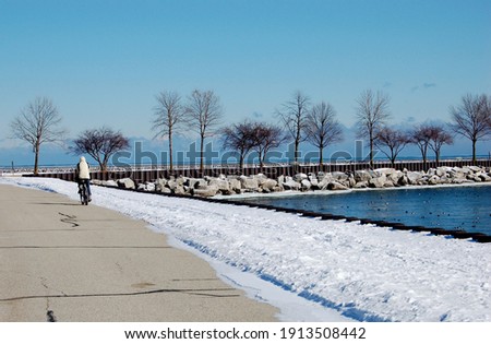 A man rides his bicycle on a cold winter day on the snowy shore of Lake Michigan in Milwaukee Wisconsin