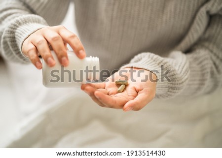 hands young women holding medical capsules, female taking supplement product or vitamin type capsule.  Royalty-Free Stock Photo #1913514430