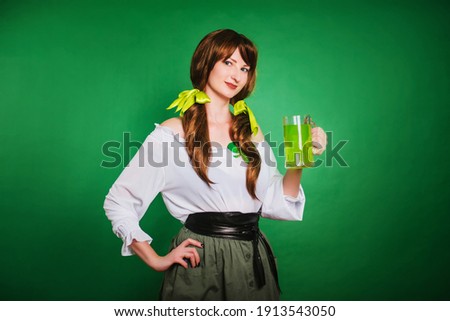 The girl celebrates st patrick's day. A woman in a medieval historical costume with a large mug of green beer. The image of a peasant woman