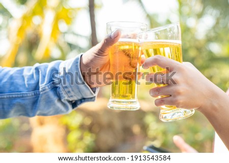 Two friends were happy toasting glasses and drinking beer on vacation.