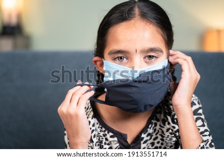 Young little girl wearing double or two face mask to protect from coronavirus or covid-19 outbreak - concept of safety, healthcare, medical and hygiene.