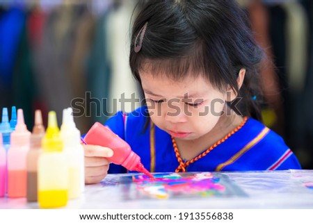 Little girl cries while she was doing crafts on table. Kids regret that artwork is damaged. Child tries to adjust her crafts look better. Working art of dripping watercolor onto template. Baby 3 years