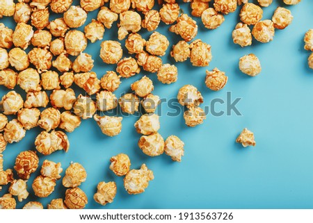 Popcorn is scattered on a blue background, in the form of a frame. Yummy for the filming of movies, TV series, cartoons. Free space, top view