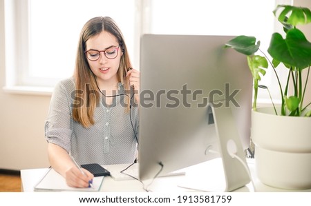 Young woman with headphones working, learning, talking on computer. High quality photo