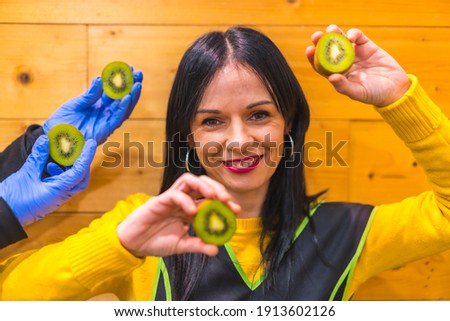 Portrait with kiwis in the hand of a brunette Caucasian fruit girl, working in a greengrocer establishment