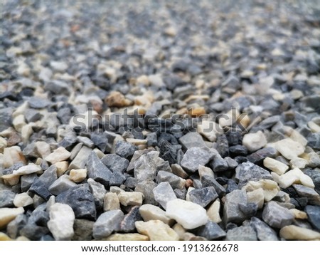 multicolor and small rocks ground texture. black small road stone background. gravel pebbles stone seamless texture. Background of crushed granite gravel, close up. focus on center and other blur.