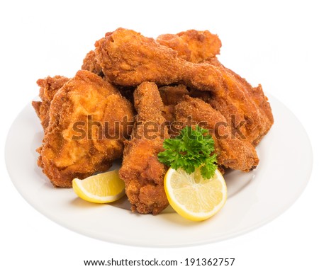 A fried chicken with lemon and parsley on a white plate