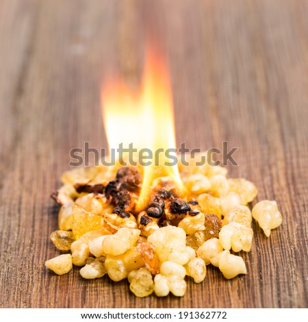 Burning incense with flame on wood