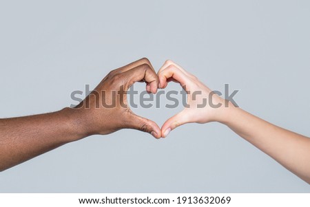 People different skin colors put their hands together making heart shape in white background. Charity, love and diversity - closeup of female and male hands of different skin color making heart shape
