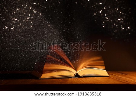 Magical image of open antique book over wooden table with glitter overlay Royalty-Free Stock Photo #1913635318