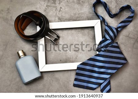 White frame with Tie, belt and cologne on a concrete background. Close up, top view. Copy space. Holidays concept Happy Father's Day, 23 February.
