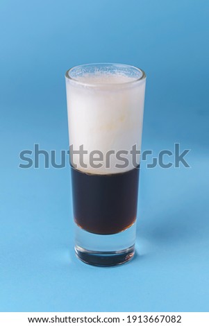 Shot cocktail collection: B52 alcohol cocktail isolated on blue background. Layered cocktail, alcoholic beverage, party concept.