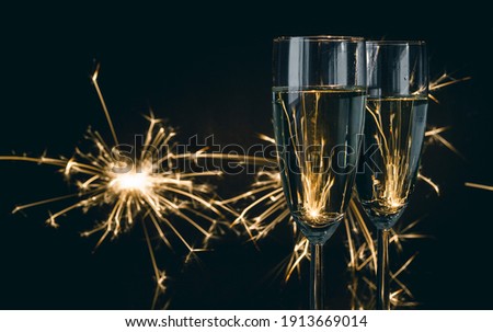Two glasses of champagne with sparklers in background. New Year's Eve celebration.