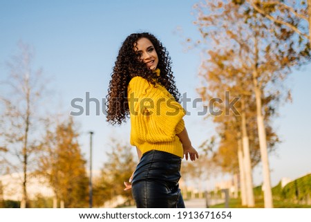 Girl in bright yellow sweater poses in autumn park. High quality photo
