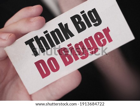 Think Big, Do Bigger. Motivation quote. Businessman holding a card with a message text written on it. Business concept.