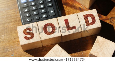 Sold. Cube wooden block with alphabet building the word SOLD and calculator. Business concept.