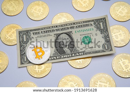 One american dollar cash on white table. Next to it are several gold bitcoin digital cryptocurrency coins. Bank image and photo background.
