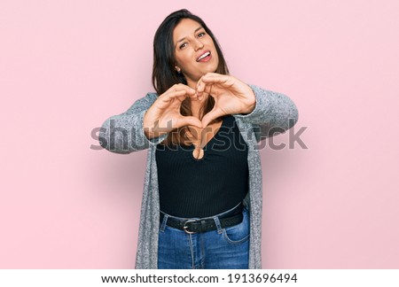 Beautiful hispanic woman wearing casual clothes smiling in love doing heart symbol shape with hands. romantic concept. 