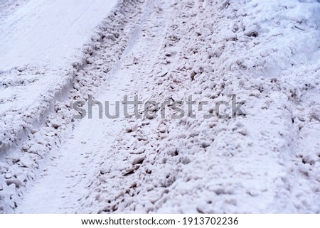 Snow-covered icy road in winter with packed snow close-up cloudy day