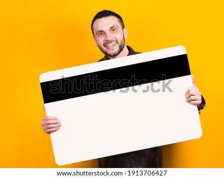 Cheerful man holding a huge bank card in his hands