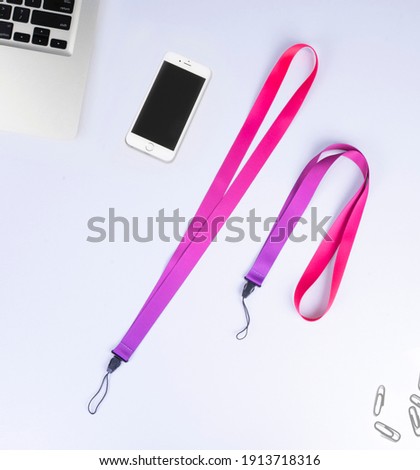 red purple Polyester Cell Phone Holder Neck Lanyard With Plastic Clip. On desk office.