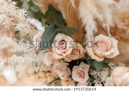 Floristic composition of cream roses, eucalyptus twigs and pampas grass. Floral background for wedding invitation or greeting card