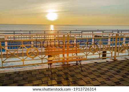 A bench on the embankment near the sea at sunrise