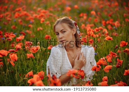 a girl in a white dress posing in a field with poppies
