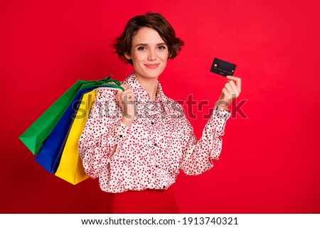 Photo portrait of girl with shopping bags holding credit card isolated on bright red colored background