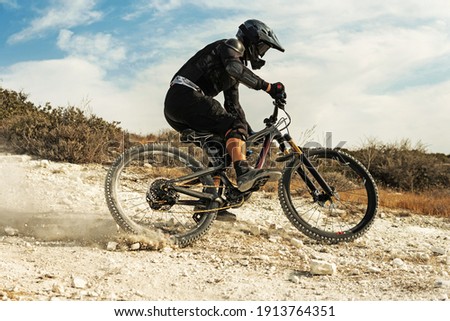 Professional bike rider fully equipped with protective gear during downhill ride on his bicycle Royalty-Free Stock Photo #1913764351