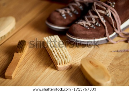 Flat lay, top view footwear with suede shoe boots care accessories, brush on wooden table. Footwear maintenance captured, copy space, for text. Royalty-Free Stock Photo #1913767303