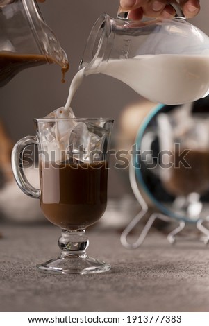 Pouring coffee and milk into a glass with ice. Preparation of ice coffee.