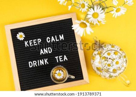 Keep calm and drink tea. Motivational quote on black letter board and herbal chamomile tea on yellow background. Concept inspirational quote of the day. Flat lay Top view.