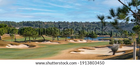Picturesque scenery golf course green field with trees blue lake during warm winter sunny day, meadow located in Las Colinas. Province of Alicante, Spain. Sport and lifestyle concept. Horizontal view
