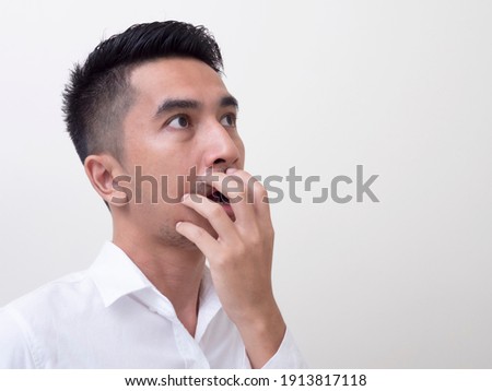 Shocked face of Asian man in white shirt on white background.