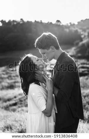 Young beautiful woman and man hug, kiss and walk in nature at sunset. Black-white photographs of a man and a woman in nature.