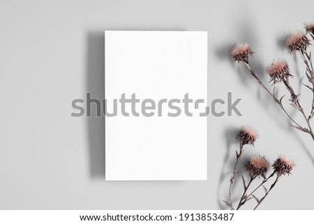 White paper empty blank, dried flowers on gray table. Invitation card mockup.Flat lay, top view, copy space, mockup