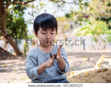 Asian cute child boy playing clay outdoor with funny face in garden. Happy kid enjoy in relaxing day, preschool learning, freedom, imagination concept.