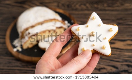Valentine star marzipan cookie. Typical christmas cinnamon star cookies with white icing in hand. Glazed star
