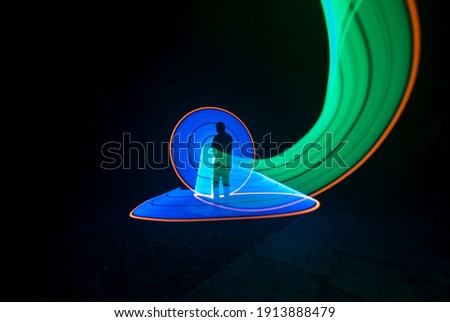 one person standing against beautiful green and blue circle light painting as the backdrop