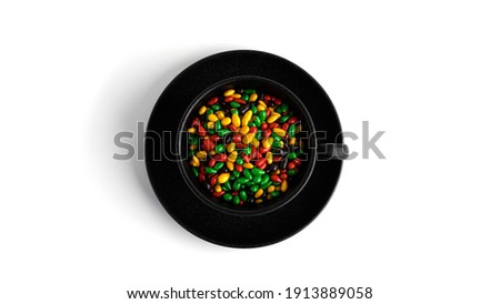 Colored chocolate sunflower seeds in black cup isolated on a white background. High quality photo