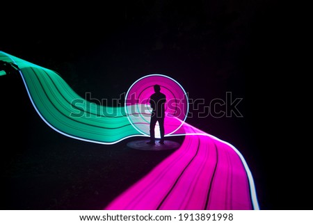 one person standing against beautiful green and violet circle light painting as the backdrop